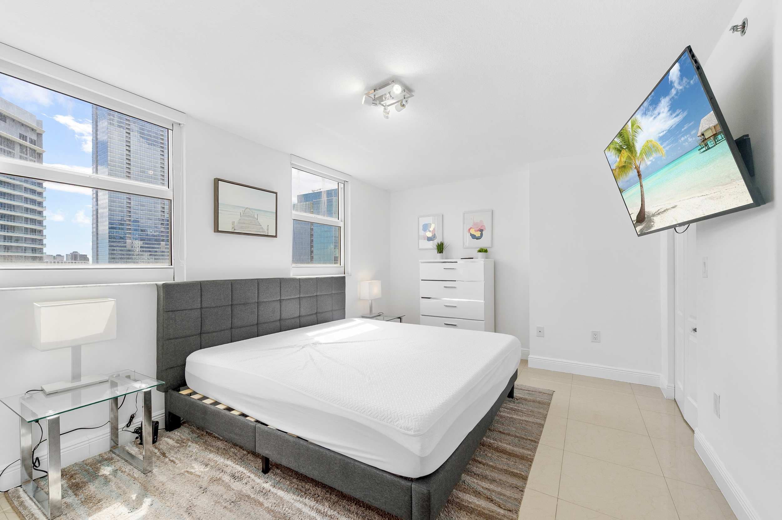Serene primary bedroom with crisp linens and a smart TV.