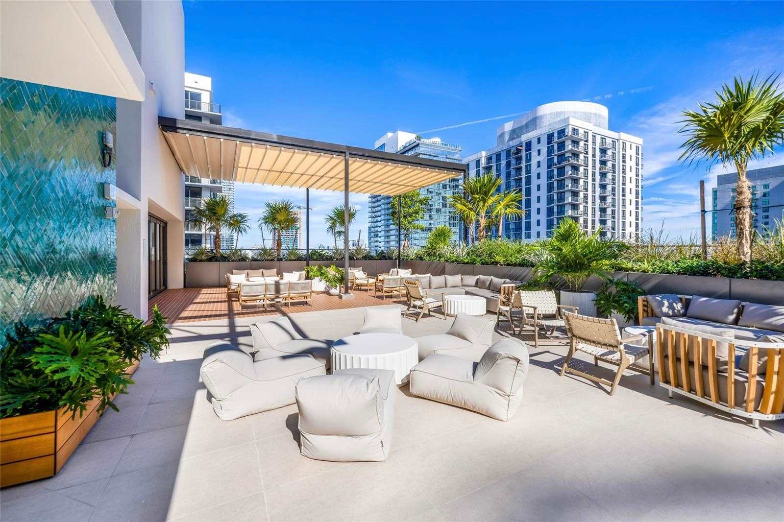Outdoor lounge with pale seats and palm trees.