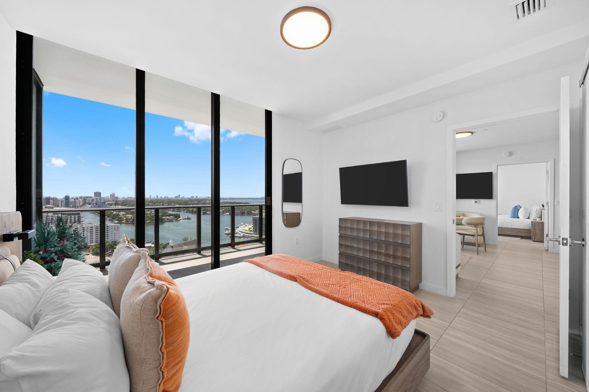 Bedroom with an orange throw and balcony doors.