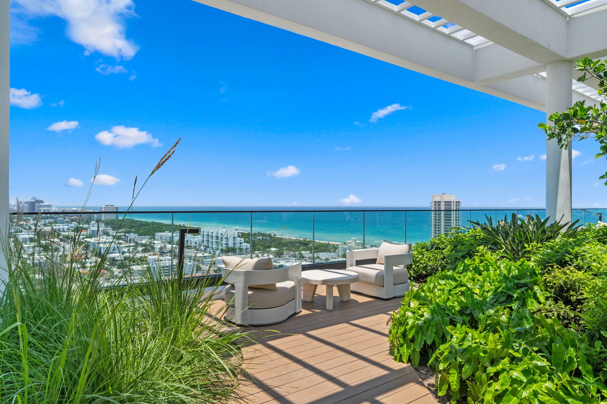 Ocean-view terrace with armchairs and greenery.