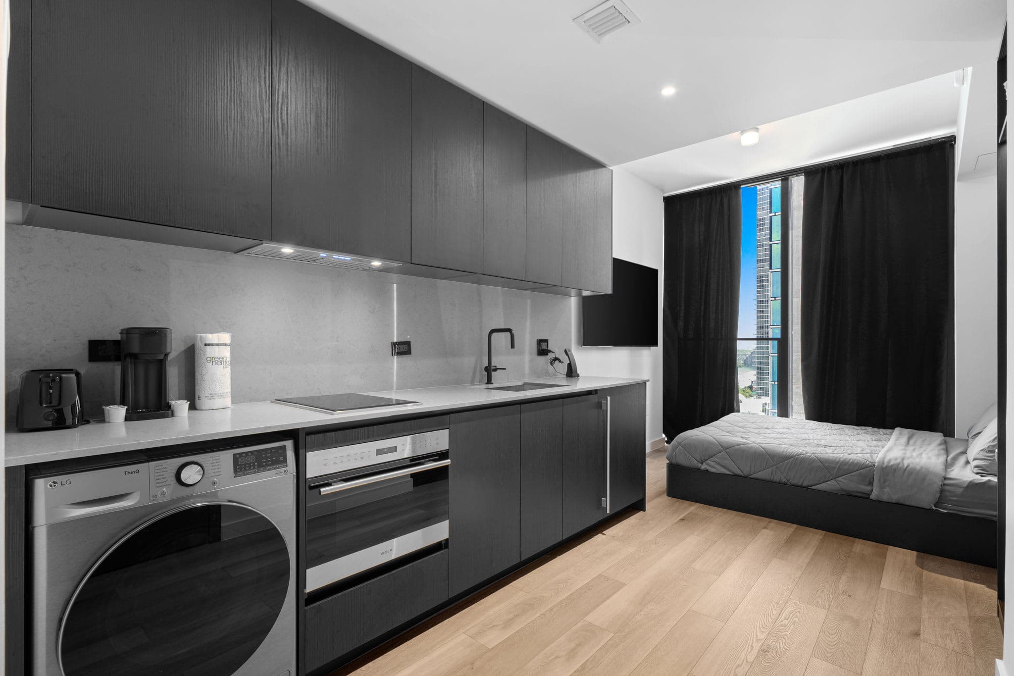 Studio kitchen with a washer beside the bed.