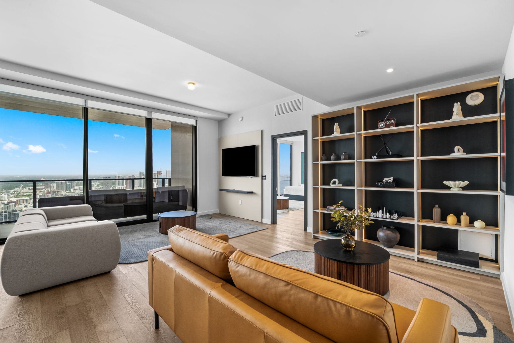 Orange sofa beside tall city-view windows.